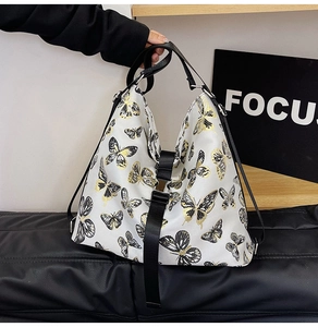 Close-up of white shoulder bag with butterfly print and black buckle closure detail