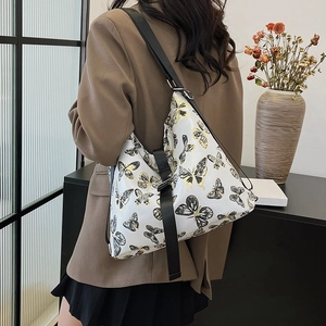 White large capacity shoulder bag with butterfly print and black wide strap on model