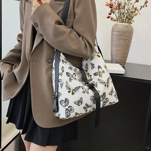 Fashionable white crossbody bag with butterfly print and adjustable black strap on model