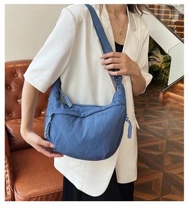 Blauwe nylon halve maan tas met brede schouderband en gevlochten knoopdetail aan rits