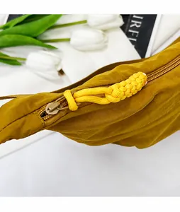 Detail van mosterdgele nylon tas met metalen rits en gevlochten touwtrekker voor accent
