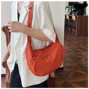 Detail van de oranje halve maan tas met gevlochten ritskoorden en fijne nylon textuur afwerking