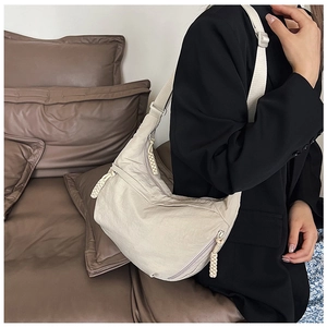 Detail van beige nylon halve maan tas met geweven rits en verstelbare schouderriem