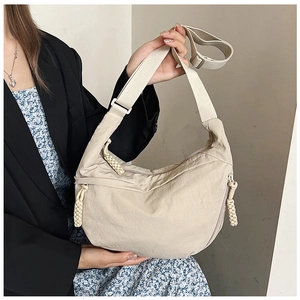 Detail van beige halve maan tas met gevlochten rits en verstelbare schouderband