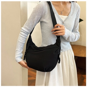 Detail van zwarte nylon halve maan tas met ritssluiting en gevlochten koordtrekkers