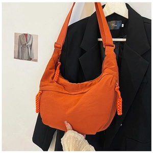 Detail van een oranje nylon halvemaantas met brede schouderriem en geweven ritskoordje