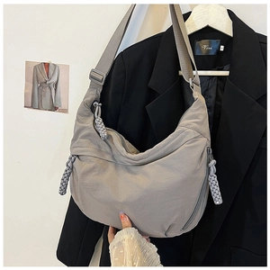 Detail van grijze nylon tas met verstelbare riem en gevlochten ritstrekker