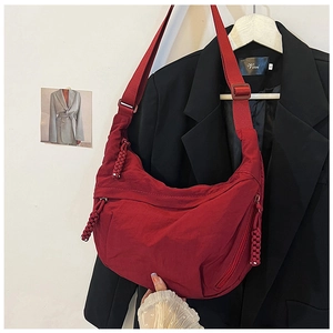 Gedetailleerd overzicht van een rode nylon crossbodytas met geknoopte ritsen.