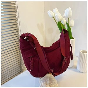 Detail van een bordeauxrode nylon halve maantas met brede schouderriem en geweven ritskoord