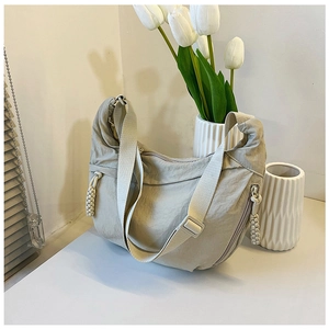 Detail van beige halve maan tas met nylon textuur en een gevlochten ritstrekker