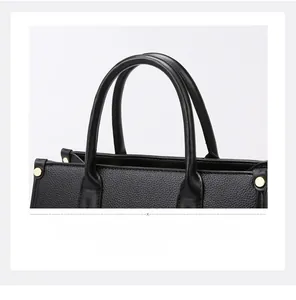 Detail der schwarzen Handtasche aus Leder mit goldenen Nieten und robusten Tragegriffen