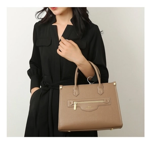 Nahaufnahme brauner Leder-Shopper mit goldenen Details und Logo an einem Model getragen