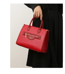 Nahaufnahme der roten Ledertasche mit feiner Litschi-Maserung und goldener Beschriftung