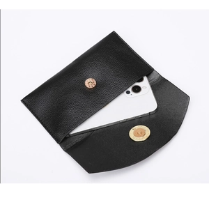 Details der schwarzen Handy-Tasche aus strukturiertem Leder mit goldener Magnetschließe