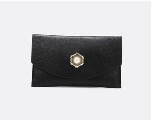 Detail der schwarzen Clutch aus genarbtem Leder mit goldener Herz-Perlenschnalle