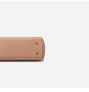 Detailed close-up of textured leather handbag base featuring protective metal feet studs