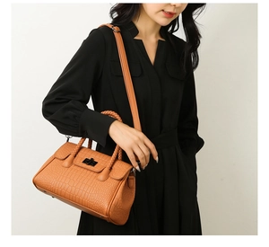 Close-up of brown crocodile pattern handbag with metal twist lock and woven handles
