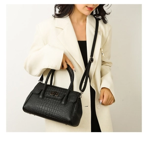 Detailed view of black crocodile pattern handbag with metal lock and shoulder strap