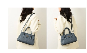 Detail of blue-grey crocodile texture handbag with woven handle and rotating metal lock