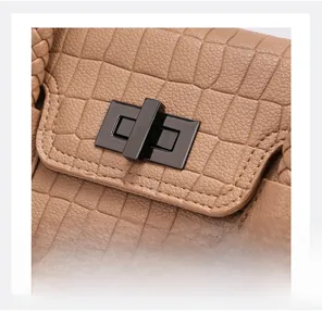 Macro shot of dark brown crocodile embossed leather with metallic twist lock and braided handle