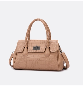 Detail of khaki crocodile-embossed leather bag with woven handle and metal twist lock
