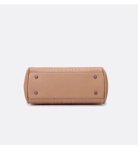 Detailed bottom view of beige handbag with crocodile texture and protective metal studs