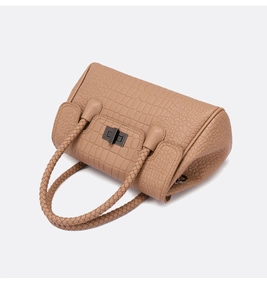 Close-up of light brown crocodile embossed handbag with woven handle and metal twist lock