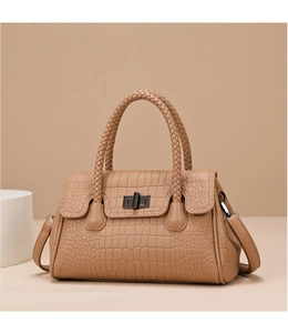 Detail of embossed crocodile pattern handbag featuring a woven handle and metal twist lock
