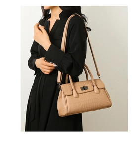 Detail of light tan crocodile embossed handbag with woven handle and metallic twist lock