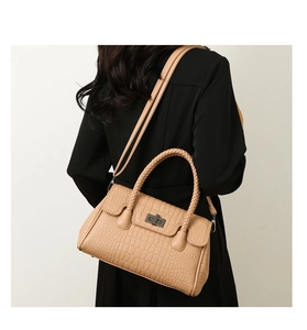 Close-up of beige crocodile embossed handbag showing woven handle and metal twist lock
