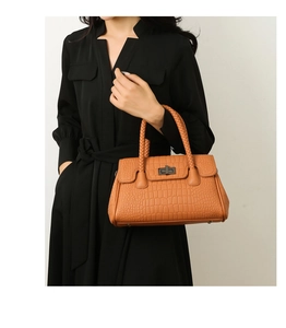 Orange-brown crocodile texture handbag featuring woven handles and metal turn-lock closure