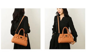 Detail of orange crocodile pattern handbag featuring a woven handle and gold twist lock
