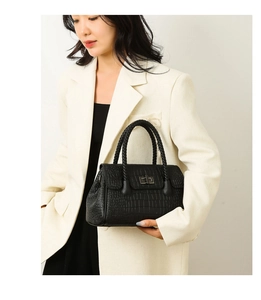 Detail of black crocodile embossed handbag with silver clasp and woven handles