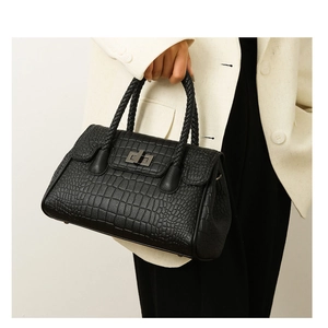 Detail of black crocodile texture handbag with woven handle and square metal twist lock