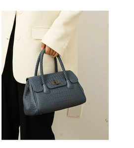 Detail of blue embossed crocodile leather handbag with woven handle and metal twist lock