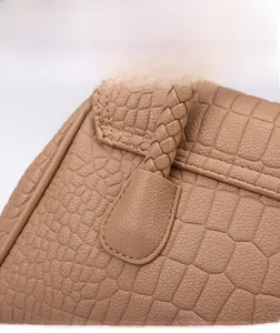 Detail view of tan crocodile embossed leather texture and woven handle craftsmanship