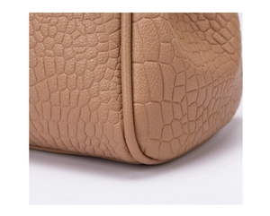 Close-up of light brown faux leather with crocodile pattern and detailed stitching