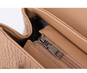 Macro view of brown lychee grain leather handbag with dark metal zipper and stitching