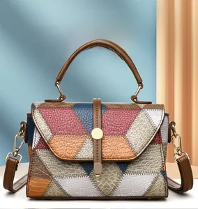 Detail of color block handbag showing pebble leather texture and gold metal buckle