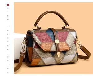 Detail of color-block leather texture and golden metal hardware on a square bag