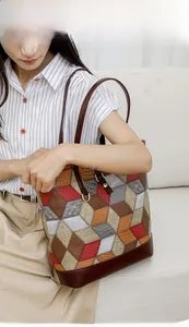 Detailed view of a multi-color geometric tote bag shown with model on a light sofa