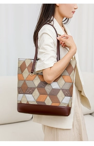 Detail of a large 3D geometric patchwork tote bag with crocodile texture and gold hardware