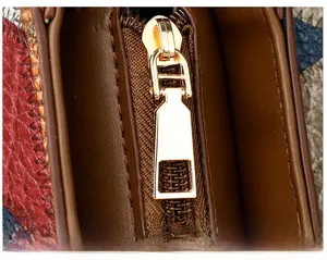 Detailed close-up of golden metal zipper pull on a multicolor lychee grain leather bag
