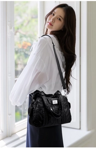 Detail shot of black soft faux leather shoulder bag with multi-pocket design on model