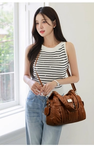 Detailed view of brown soft leather tote bag featuring braided texture and multi-zip design