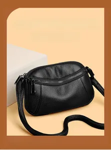 Detail shot of black pebbled leather texture and unique curved zipper on cross-body bag