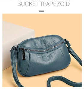 Detail of navy blue pebble leather trapezoid bucket bag with silver zipper and strap