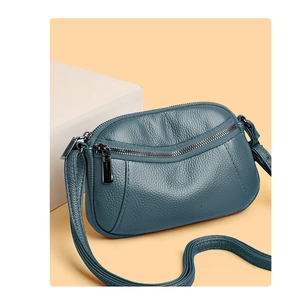Close-up of blue textured leather crossbody bag showing lychee grain and silver zippers