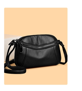 Close-up of black litchi grain leather crossbody bag with curved zipper detail
