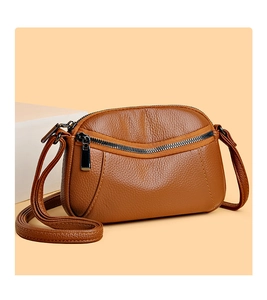 Detail of brown litchi pattern leather crossbody bag with curved zipper and shell shape